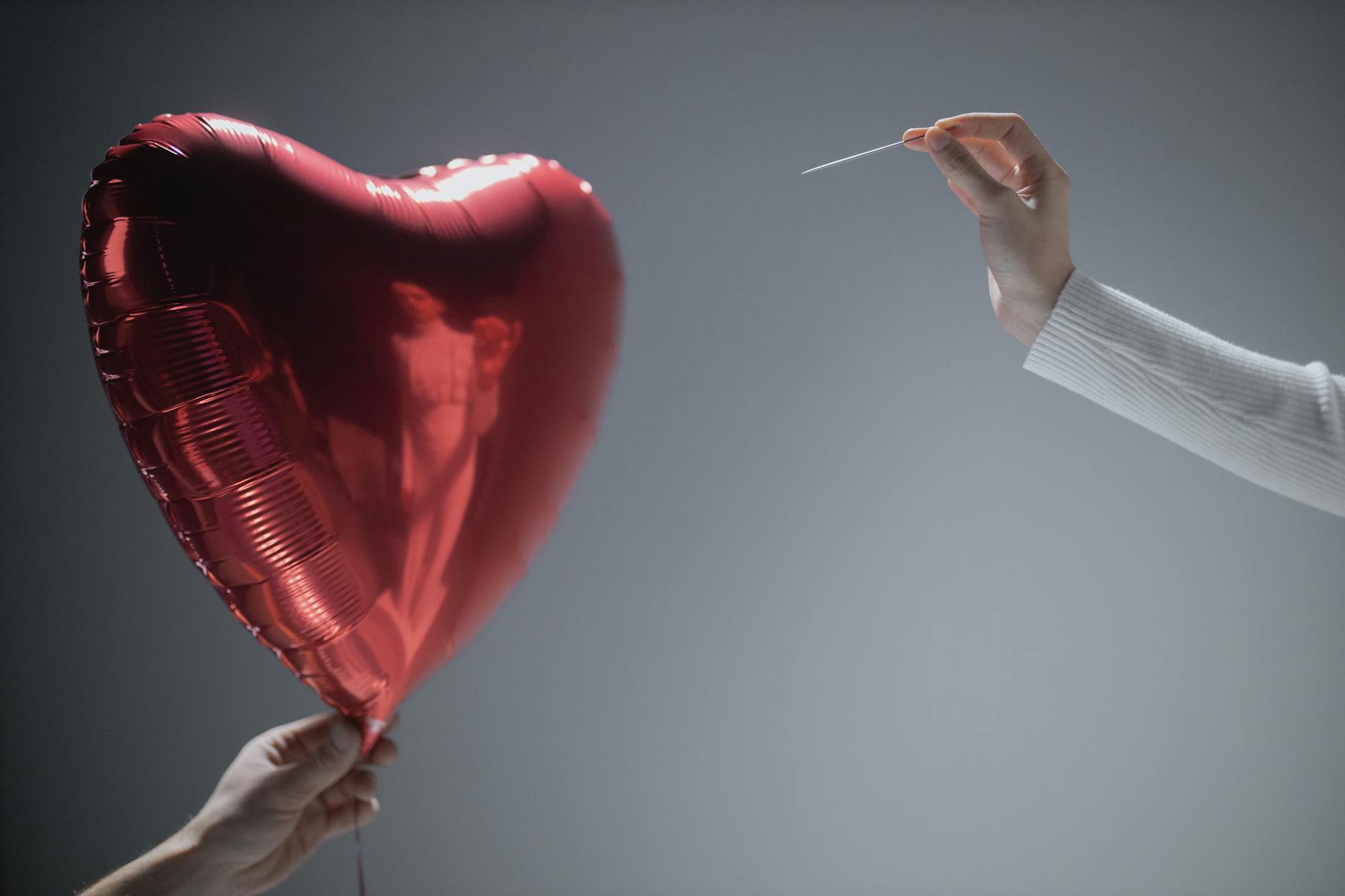 person holding red heart balloon